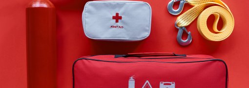 © flache Lage mit Feuerlöscher, Kfz-Handtasche, Erste-Hilfe-Set und Auto-Abschleppseil auf rotem Hintergrund - LightFieldStudios Diese Dinge sollten Sie im Auto immer dabei haben