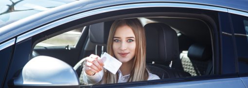 © Fröhliches Mädchen beim Fahren eines Trainingswagens mit einer Führerscheinkarte in der Hand - Kobrinphoto 4. Führerscheinrichtlinie der EU: Das ändert sich