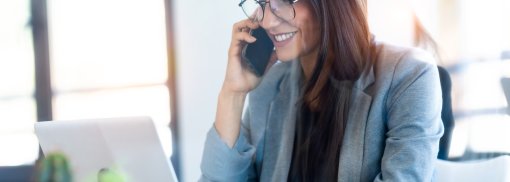 © Lächelnde Geschäftsfrau im Gespräch auf dem Handy - nenetus Welche Fragen sollten Sie vor einem Gebrauchtwagenkauf am Telefon stellen?