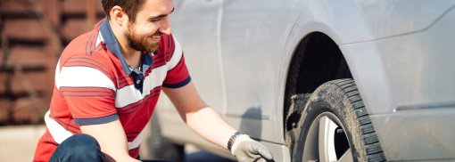 © Smiling man and mechanic changing tyres - stockcentral Sommer- und Winterreifen oder Ganzjahresreifen - Was sind die Vor- und Nachteile?